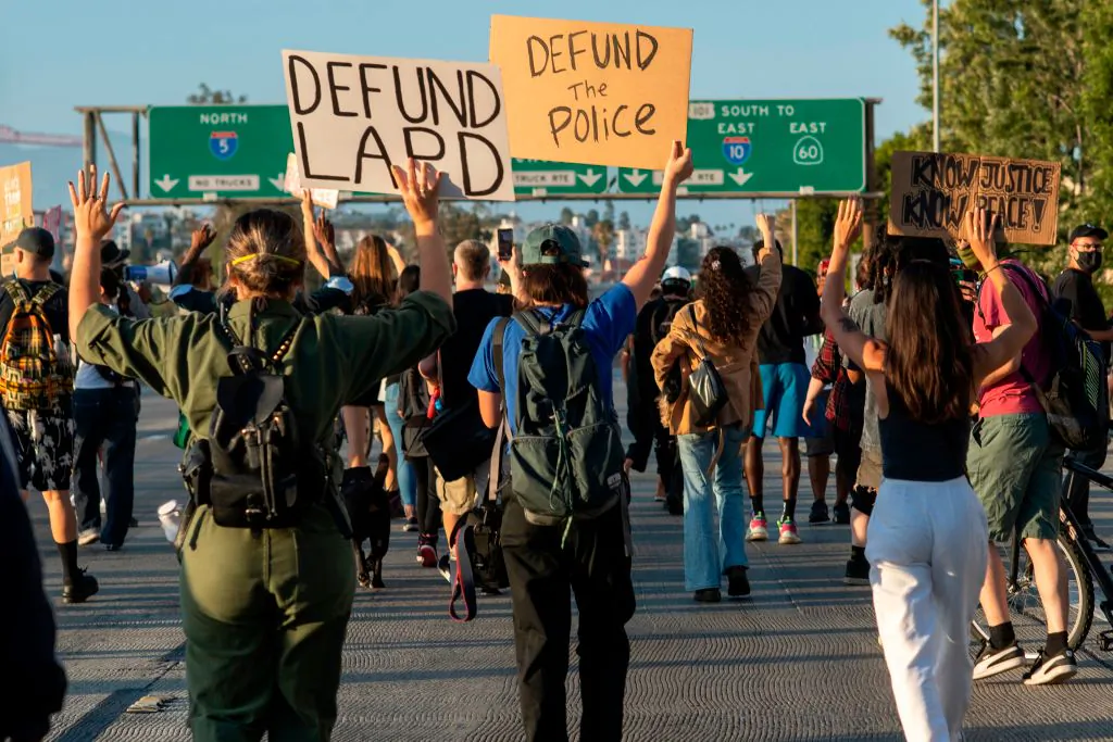 Protesters hold signs as they block the freeway during a demonstration calling for the removal of District Attorney Jackie Lacey and to defund the police, in Los Angeles, on July 1, 2020. (Valerie Macon/AFP via Getty Images)
