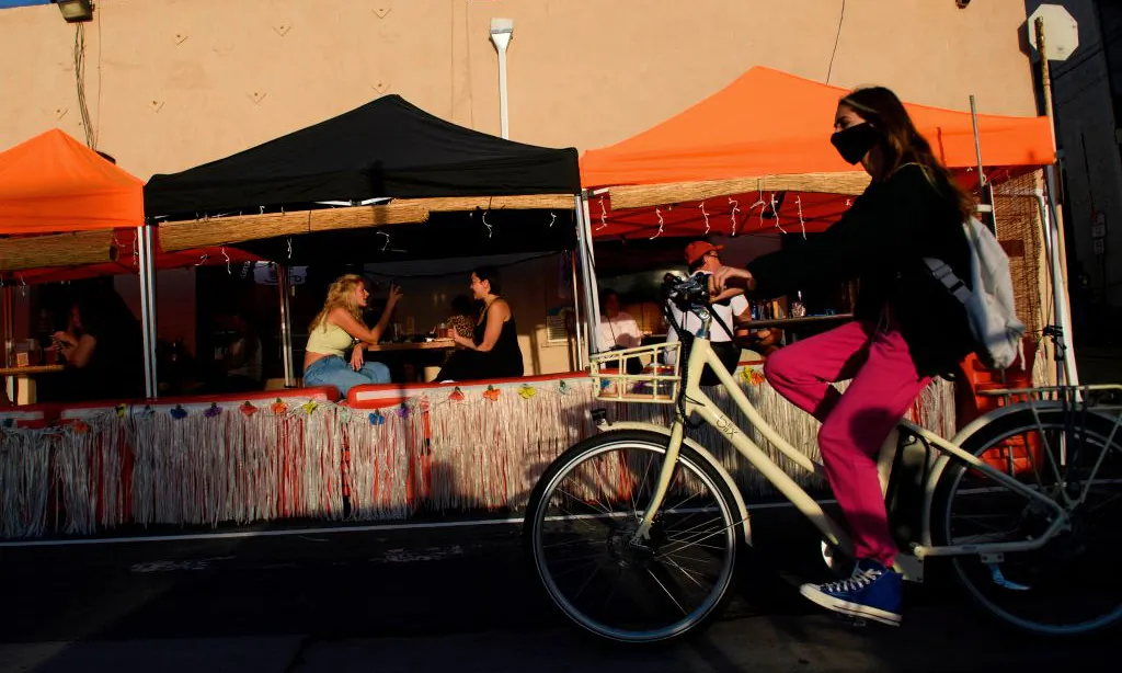 A cyclist wearing a face mask rides past outdoor diners in Manhattan Beach, Calif., on Nov. 21, 2020. (Patrick T. Fallon/AFP via Getty Images)