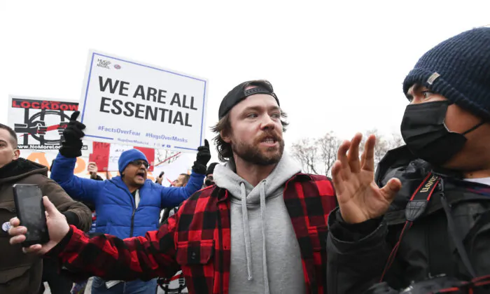 Adam Skelly (C), owner of Adamson Barbecue, escorts a photographer from his property after defying provincial lockdown orders to shut down indoor and outdoor dining during the COVID-19 pandemic in Toronto, Canada, on Nov. 25, 2020. (The Canadian Press/Nathan Denette)