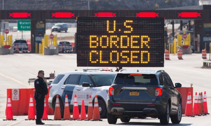 U.S. Customs officers speak with people in a car beside a sign saying that the U.S./Canada border is closed in Lansdowne, Ontario, Canada, on March 22, 2020. (Lars Hagberg/AFP via Getty Images)