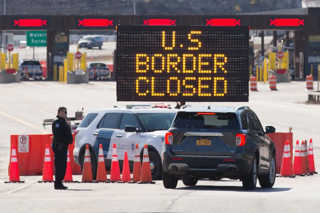 U.S. Customs officers speak with people in a car beside a sign saying that the U.S./Canada border is closed in Lansdowne, Ontario, Canada, on March 22, 2020. (Lars Hagberg/AFP via Getty Images)