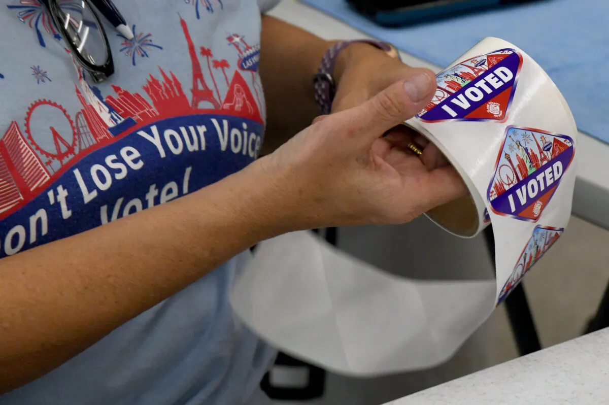 A poll worker unrolls Las Vegas Strip-themed "I Voted" stickers for voters at a polling place at the Veterans Memorial Leisure Center in Las Vegas, Nevada, on Nov. 3, 2020. (Ethan Miller/Getty Images)