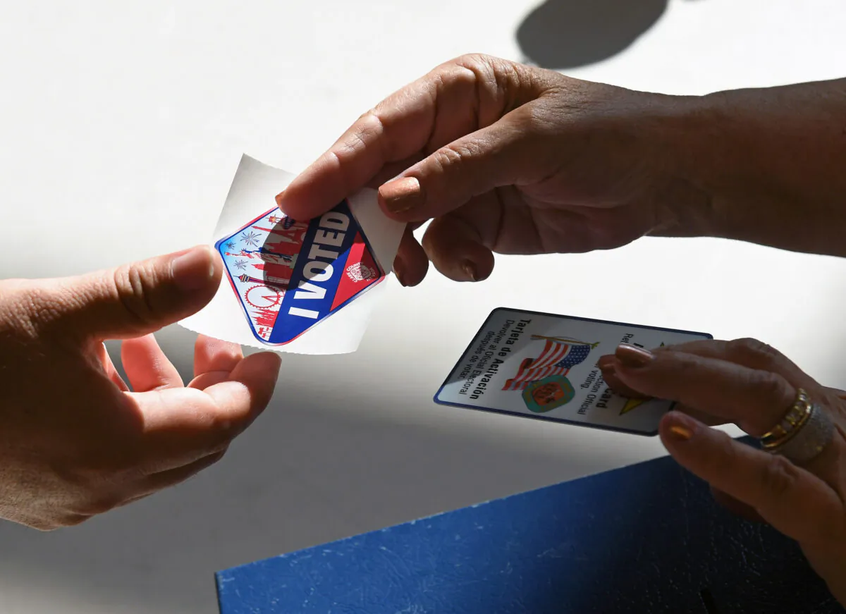 A poll worker gives a voter a Las Vegas Strip-themed "I Voted" sticker after taking back her voter activation card at a polling station at Cheyenne High School on Election Day in North Las Vegas, Nev., on Nov. 8, 2016. (Ethan Miller/Getty Images)