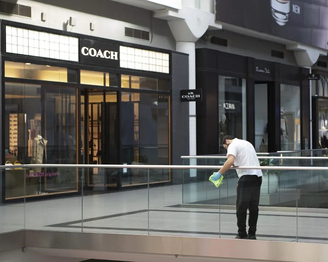 A cleaner wipes a glass panel at Toronto's Eaton Centre Shopping mall on March 21, 2020. (The Canadian Press/Chris Young)