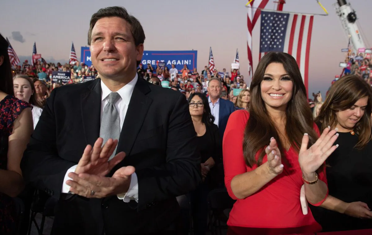 Florida Gov. Ron DeSantis (L) and Kimberly Guilfoyle (R), finance chair of U.S. President Donald Trump's campaign, applaud as Trump holds a Make America Great Again rally as he campaigns at Orlando Sanford International Airport in Sanford, Fla., on Oct. 12, 2020. (Saul Loeb/AFP via Getty Images)