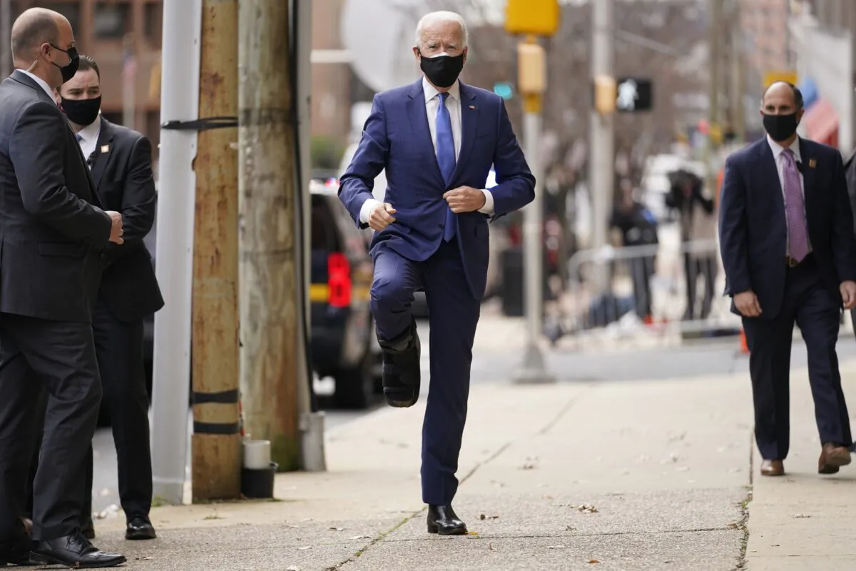 Democratic presidential nominee Joe Biden raises a leg while wearing a walking boot, as he arrives at the Queen Theater in Wilmington, Del., on Dec. 1, 2020. (Andrew Harnik/AP Photo)