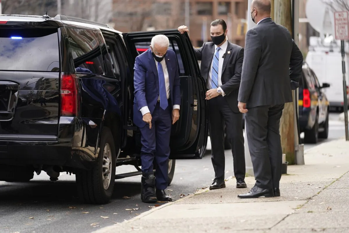 Democratic presidential candidate Joe Biden points to the walking boot he's wearing as he arrives at the Queen Theater in Wilmington, Del., on Dec. 1, 2020. (Andrew Harnik/AP Photo)
