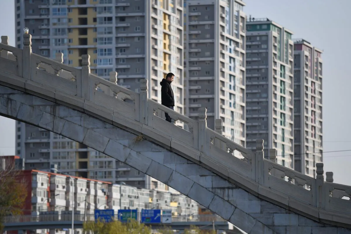 A man crosses a bridge near an apartment complex in Beijing on Dec. 1, 2020. (Greg Baker/AFP via Getty Images)