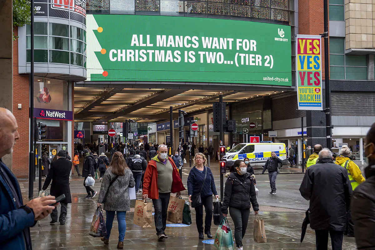 Shoppers walk past COVID-19 signage displayed on the Arndale in the city centre as Manchester, England, enters Tier 3 on Dec. 2, 2020 (Anthony Devlin/Getty Images)