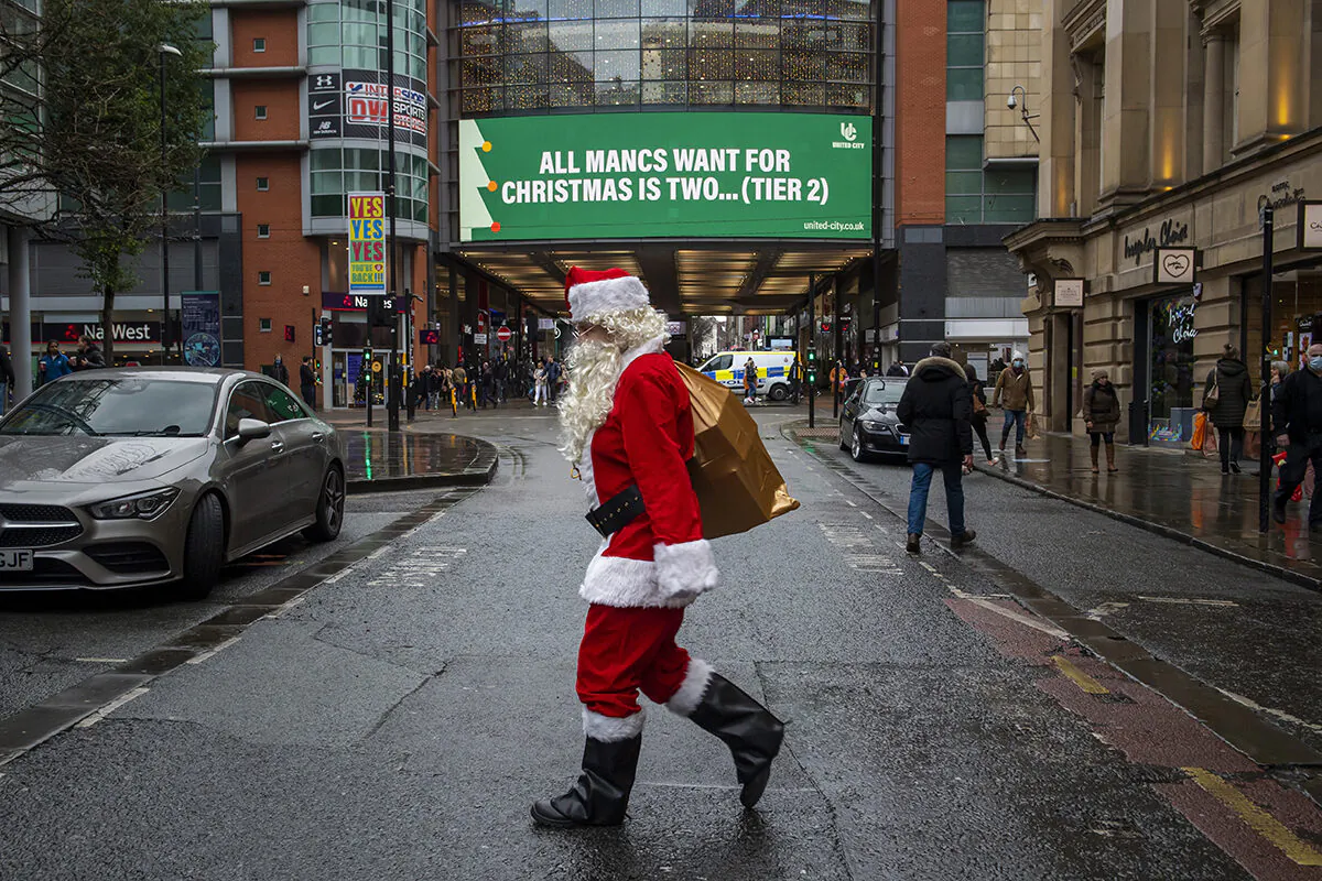 A man dressed as Father Christmas walks past COVID-19 signage in Manchester, England, on Dec. 2, 2020. (Anthony Devlin/Getty Images)