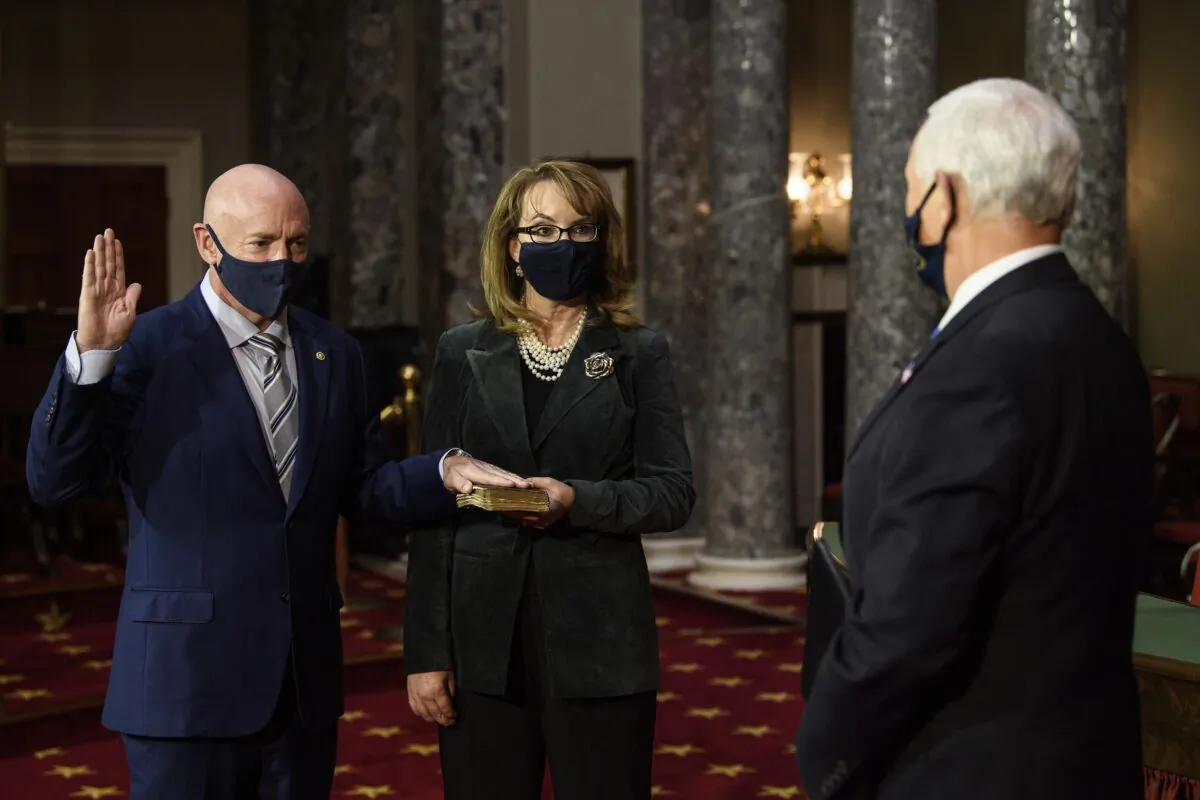 Sen. Mark Kelly, (D-Ariz.), with his wife, former Rep. Gabby Giffords (D-Ariz)., participates in a re-enactment of his swearing-in  by Vice President Mike Pence in the Old Senate Chamber on Capitol Hill in Washington on Dec. 2, 2020. (Nicholas Kamm/Pool via AP)