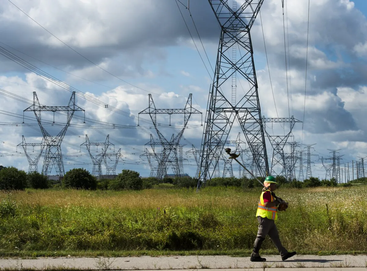 A worker walks past rows of power lines with his weed whacker in Mississauga, Ont., Canada, on Aug. 19, 2019. (Nathan Denette/The Canadian Press)