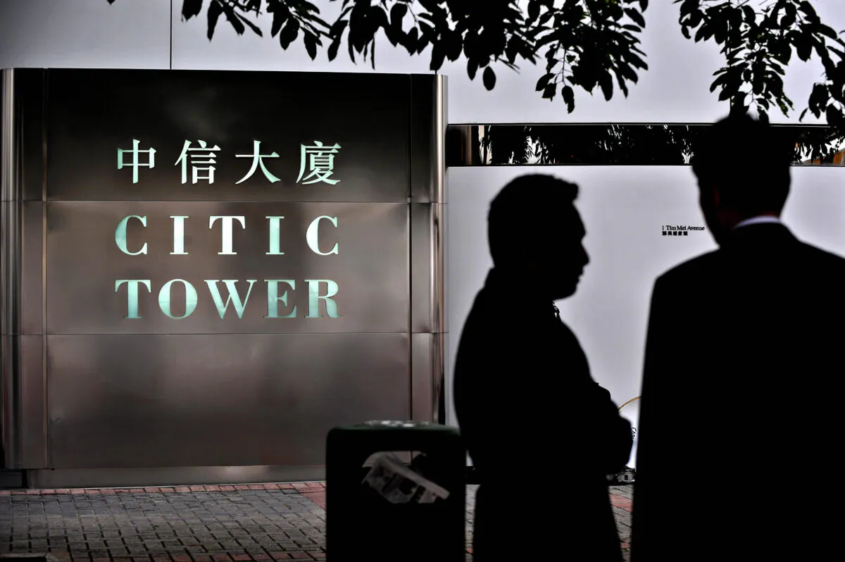 Two men chat next to the offices of CITIC Pacific in Hong Kong, on April 8, 2009. (Philippe Lopez/AFP via Getty Images)