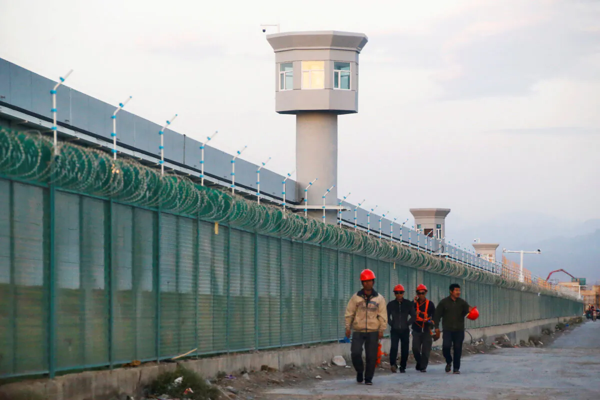 Workers walk by a concentration camp, officially known as a "vocational skills education center," in Dabancheng, Xinjiang region of China, on Sept. 4, 2018. (Thomas Peter/Reuters/File Photo)