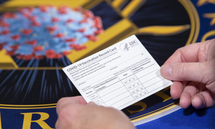 A Department of Health and Human Services employee holds a COVID-19 vaccine record card in Washington on Nov. 13, 2020. (EJ Hersom/DoD)