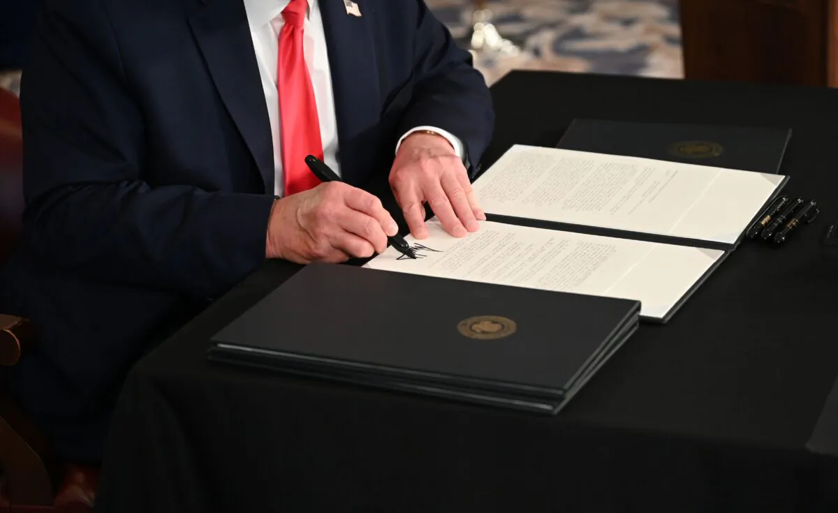 President Donald Trump signs an executive order in a file photo taken in Bedminster, N.J., on Aug. 8, 2020. (Jim Watson/AFP via Getty Images)