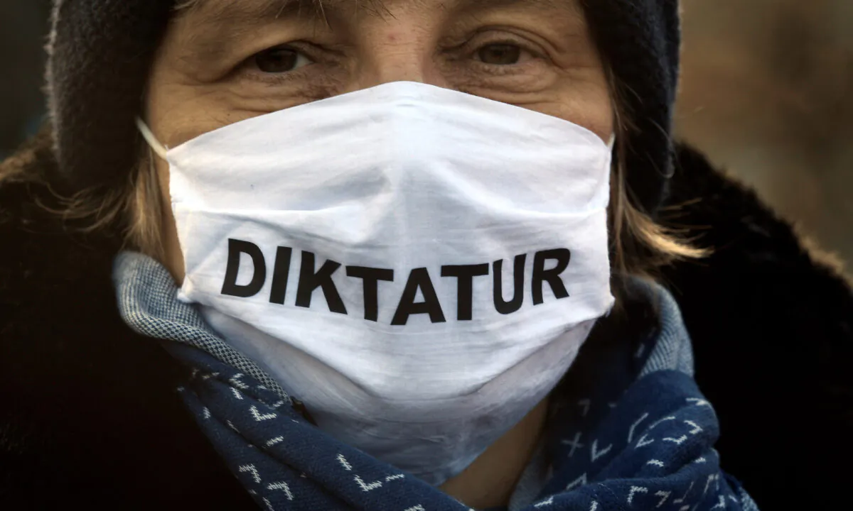 A woman wearing a protective face mask reading ''dictatorship'' protests against government restrictions, although the rally has been disallowed by a regional court, amid the CCP virus disease (COVID-19) outbreak, in Bremen, Germany, on Dec. 5, 2020. (Fabian Bimmer/Reuters)