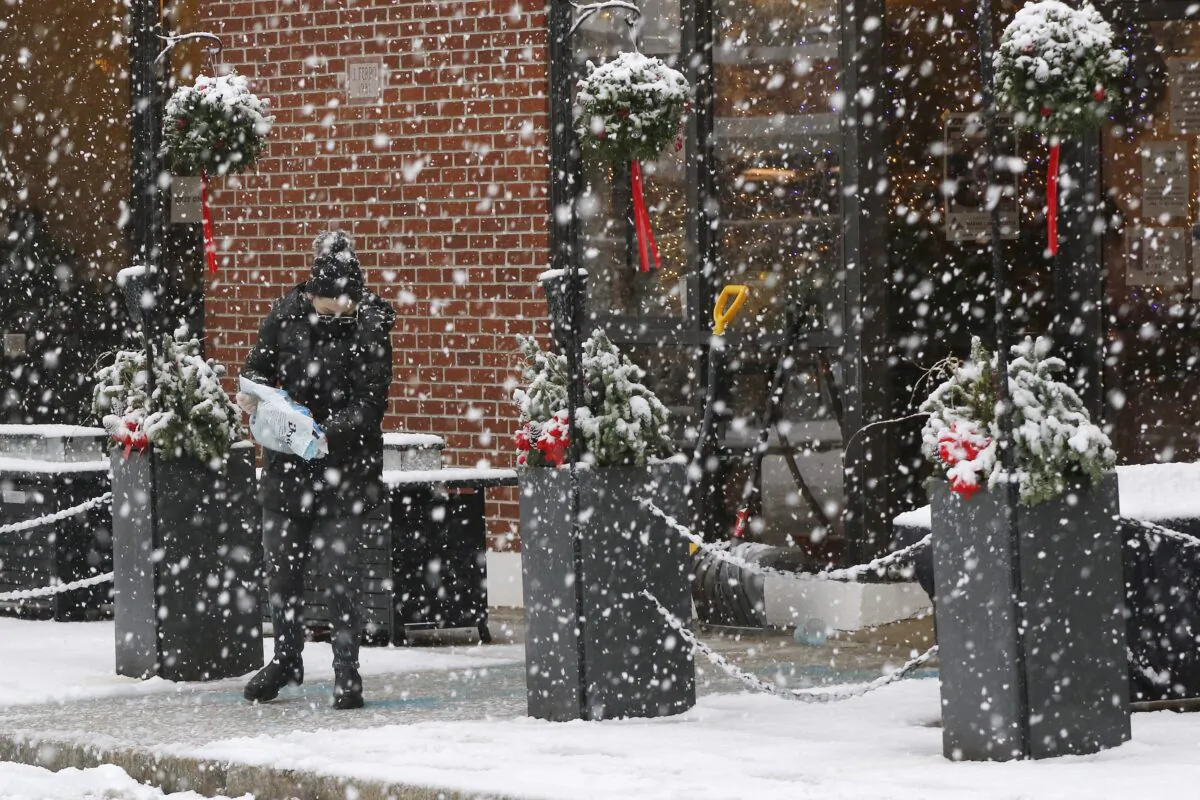 A worker pours ice melting pellets on the walkway outside a restaurant in Marlborough, Mass., on Dec. 5, 2020. (Bill Sikes/AP Photo)