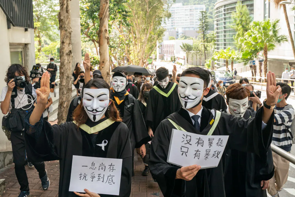 Students wearing black graduation gowns and Guy Fawkes masks march at the Chinese University of Hong Kong campus in Hong Kong on Nov. 19, 2020. (Anthony Kwan/Getty Images)