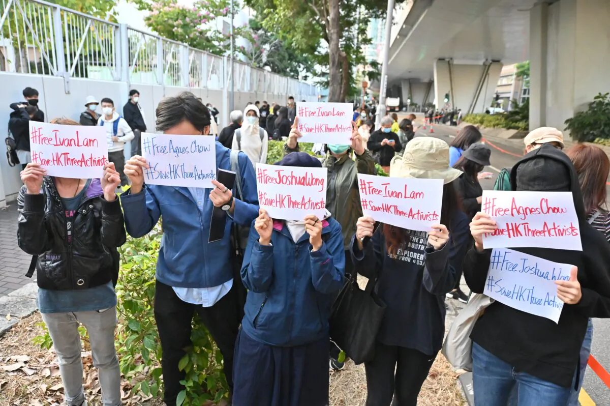 Pro-democracy supporters show signs for local activists Agnes Chow, Ivan Lam, and Joshua Wong, outside a court in Hong Kong on Dec. 2, 2020, after they were sentenced to jail terms. (PETER PARKS/AFP via Getty Images)