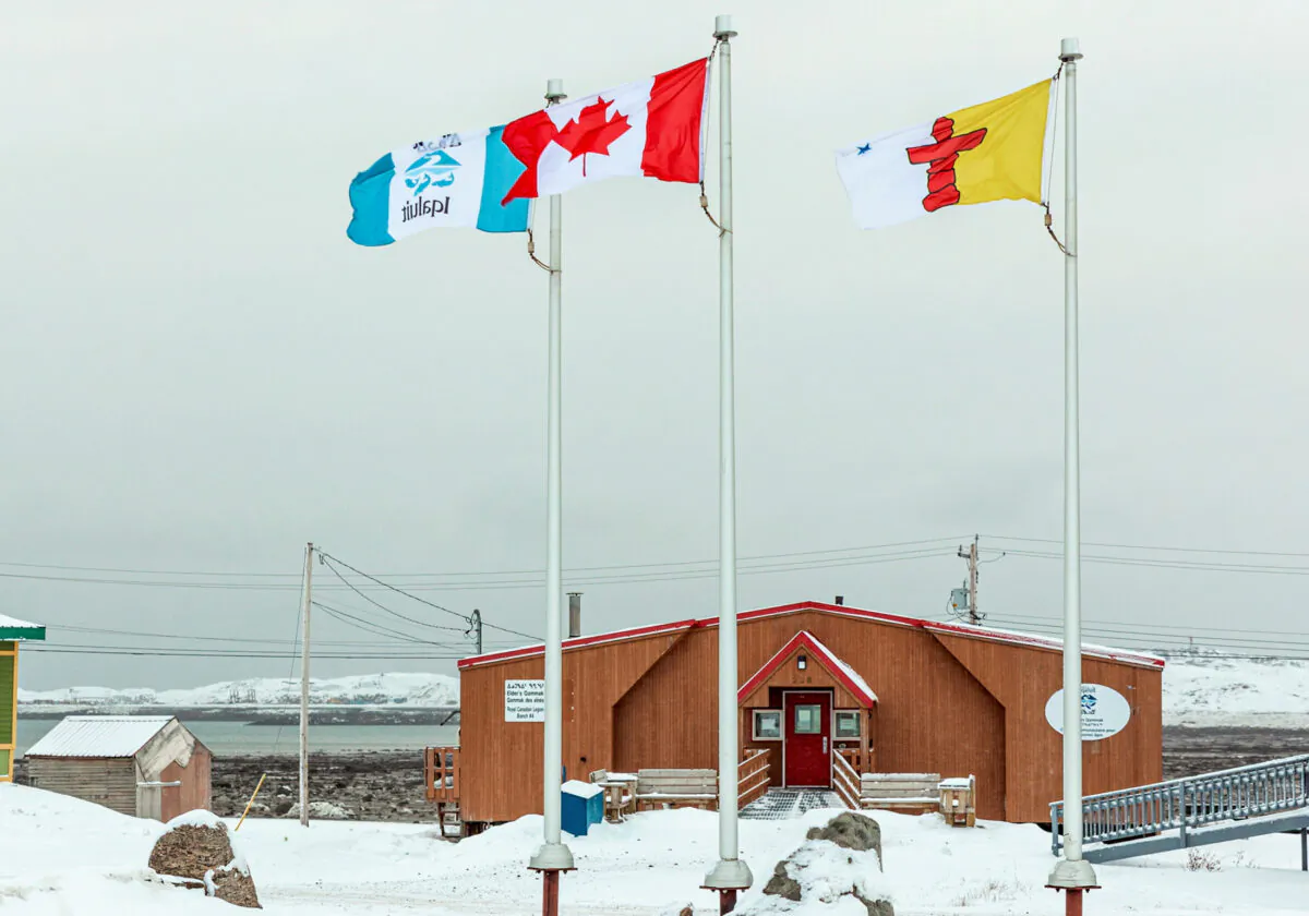 Flags of Iqaluit, Canada and the territory of Nunavut fly over the Elders' Qammaq, a drop-in centre, as Nunavut enters a two week mandatory coronavirus disease (COVID-19) restriction period in Iqaluit, Nunavut, Canada November 18, 2020.  (Reuters/Natalie Maerzluft/File Photo)