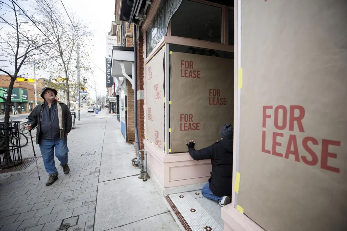 A worker posts fake “for lease” signage on a storefront in the Roncesvalles neighbourhood of Toronto as part of a protest against the Ontario government's pandemic lockdown rules, on Nov. 24, 2020. (The Canadian Press/Cole Burston)