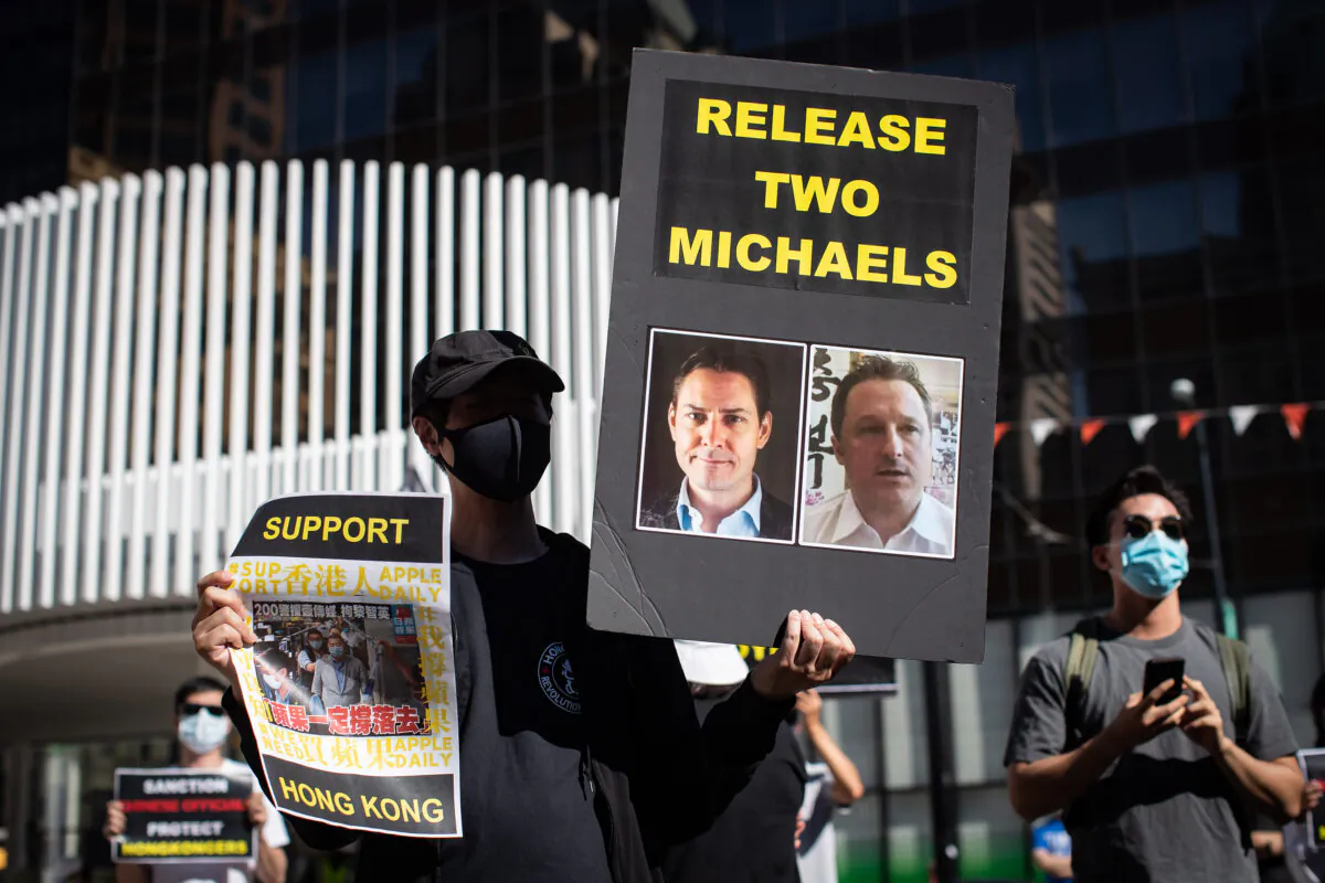 A person holds a sign with photographs of Michael Kovrig and Michael Spavor, who have been detained in China since Dec. 10, 2018, as people gather for a rally in support of Hong Kong democracy, in Vancouver on Aug. 16, 2020. (The Canadian Press/Darryl Dyck)