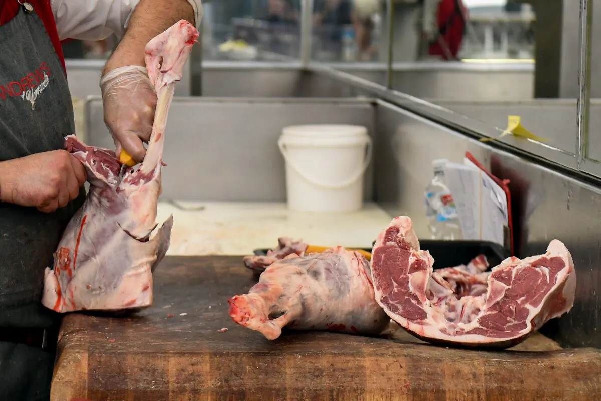 Butcher George Vourvahakis cuts up a leg of Australian lamb at his store in the Melbourne suburb of Yarraville on May 12, 2020. (William West/AFP via Getty Images)
