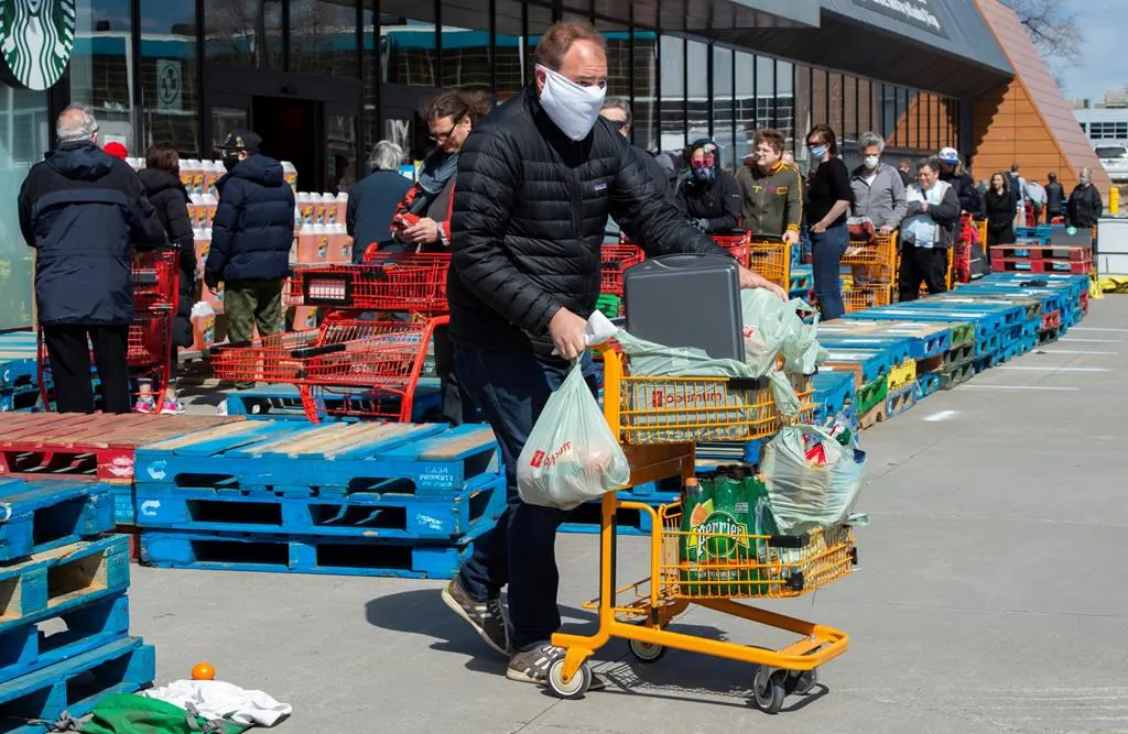 Long lines of masked shoppers wait to shop for groceries in Toronto on April 9, 2020. (The Canadian Press/Frank Gunn)