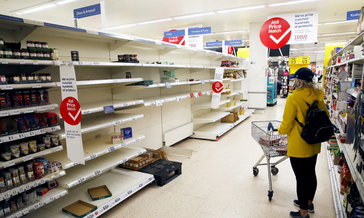 A lone shopper looks at empty shelves in a supermarket in Manchester, England, on March 18, 2020. (Clive Brunskill/Getty Images)