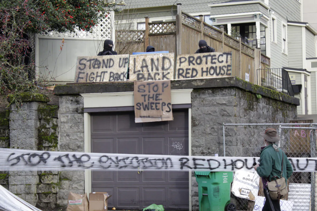 Masked individuals at an occupied home speak with a neighborhood resident in Portland, Ore., on Dec. 9, 2020. (Gillian Flaccus/AP Photo)