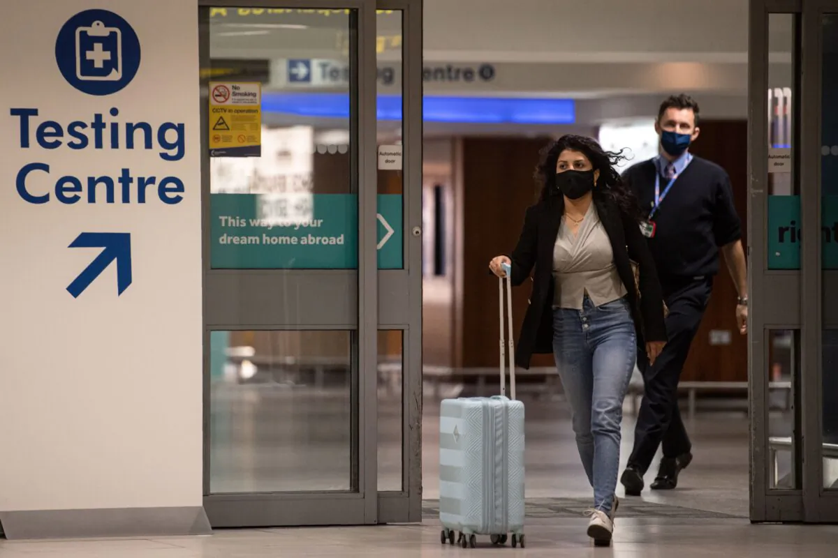 A passenger walks past a sign directing people to a CCP virus testing site adjacent to Terminal 1 of Manchester Airport in Manchester, northern England, on Dec. 3, 2020. (Oli Scarff/AFP via Getty Images)