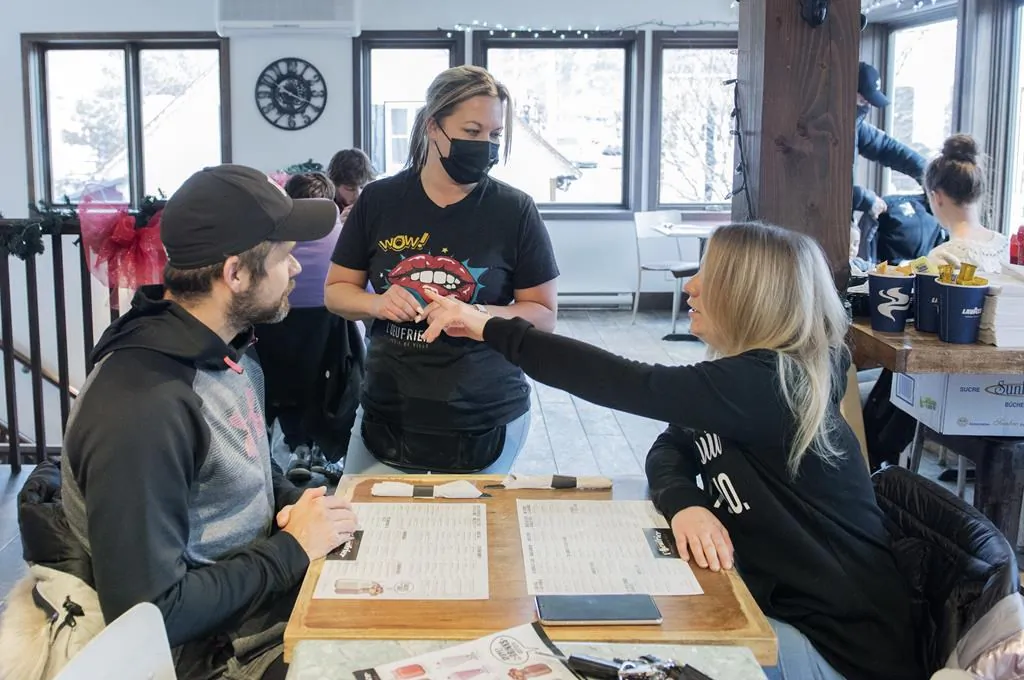A waitress takes an order from customers at a restaurant in Saint-Sauveur, Que., on Dec. 12, 2020, as the COVID-19 pandemic continues in Canada and around the world. (The Canadian Press/Graham Hughes)