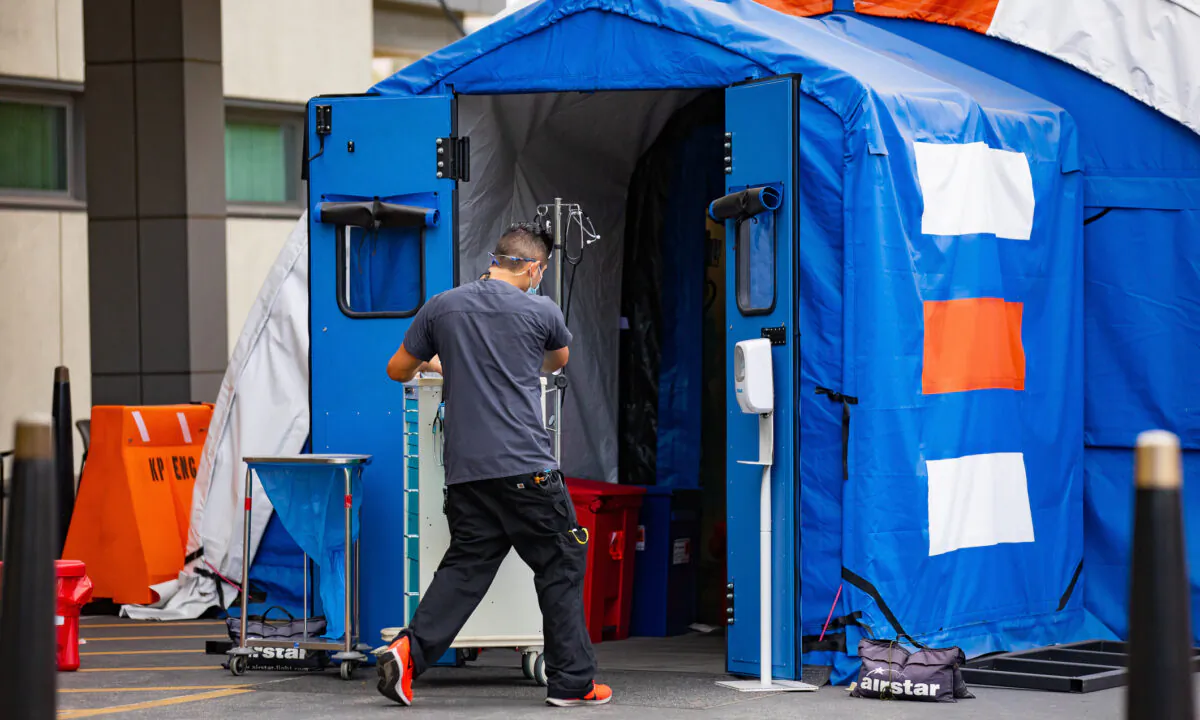 A hospital worker walks equipment into an emergency triage tent set up outside of Kaiser Permanente's Orange County Medical Center in Irvine, Calif., on Dec. 11, 2020. (John Fredricks/The Epoch Times)