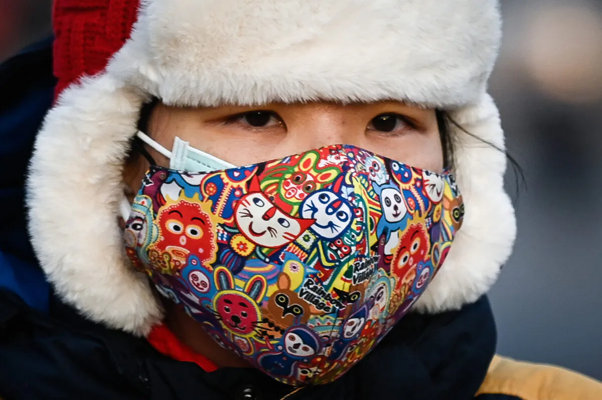 A woman wearing a face mask rides an electric bicycle along a street in Beijing, on Dec. 10, 2020. (WANG ZHAO/AFP via Getty Images)