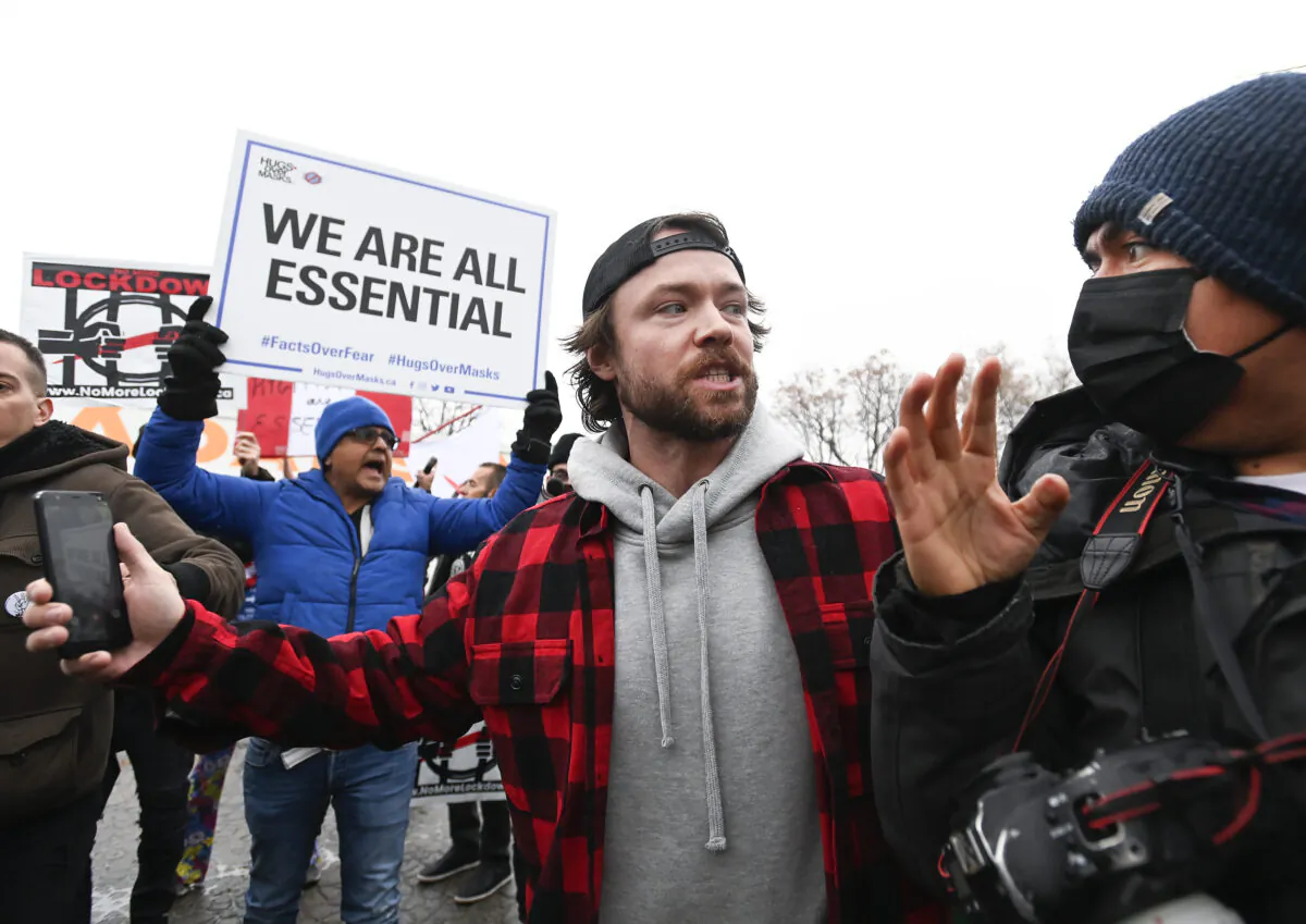 Adam Skelly, centre, owner of Adamson Barbecue, escorts a photographer from his property after defying provincial lockdown orders to shut down indoor and outdoor dining during the COVID-19 pandemic in Toronto, Canada, on Nov. 25, 2020. (Nathan Denette/The Canadian Press)
