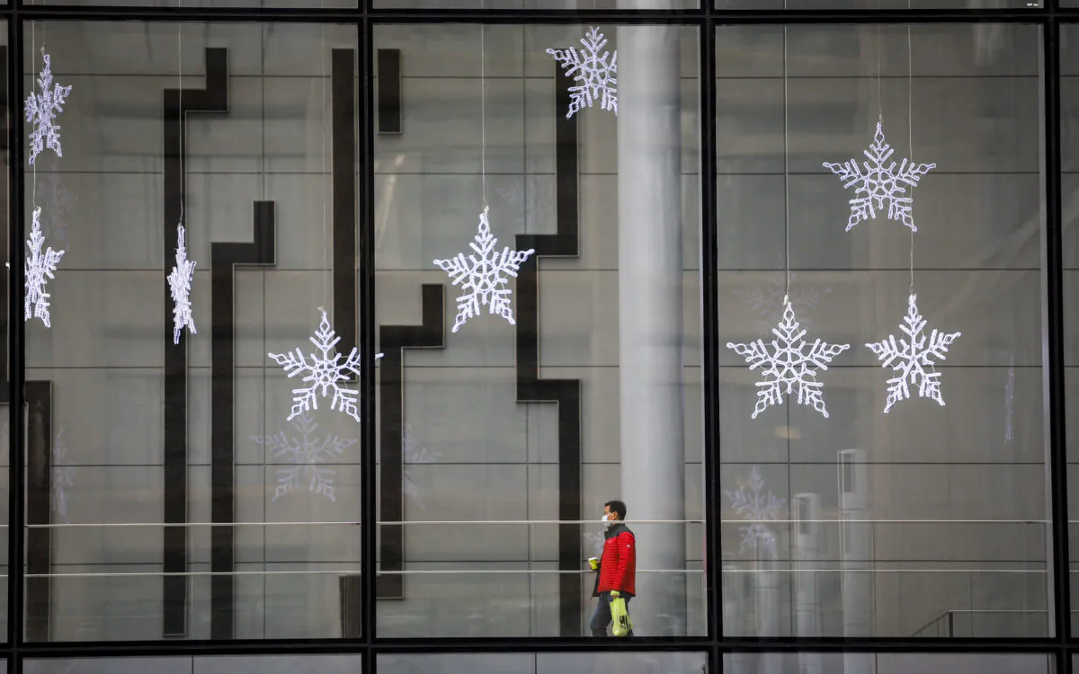 A pedestrian walks beneath Christmas decorations in an empty downtown Calgary on Dec. 9, 2020, after new provincial restrictions were announced amid the COVID-19 pandemic. (Jeff McIntosh/The Canadian Press)