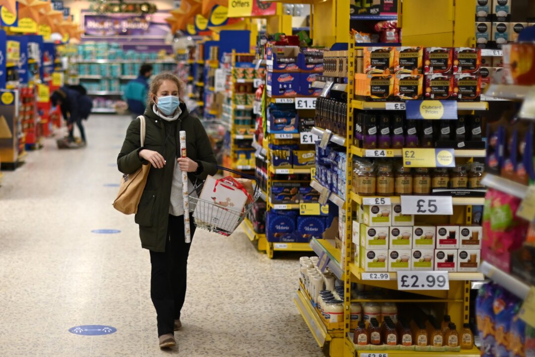 A shopper wearing a protective face covering walks the aisles of a Tesco supermarket in London on Dec. 14, 2020. (Daniel Leal-Olivas/AFP via Getty Images)