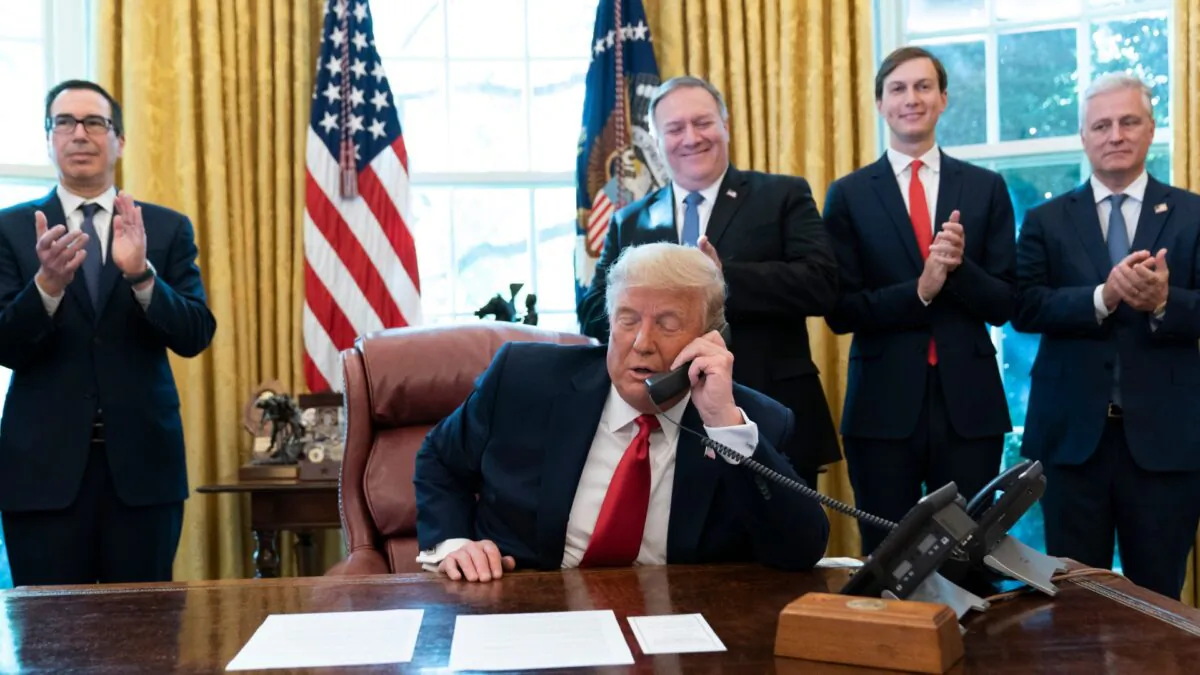 President Donald Trump talks on a phone call with the leaders of Sudan and Israel, as Treasury Secretary Steven Mnuchin (L), Secretary of State Mike Pompeo, White House senior adviser Jared Kushner, and National Security Adviser Robert O'Brien applaud in the Oval Office of the White House on Oct. 23, 2020. (Alex Brandon/AP Photo)