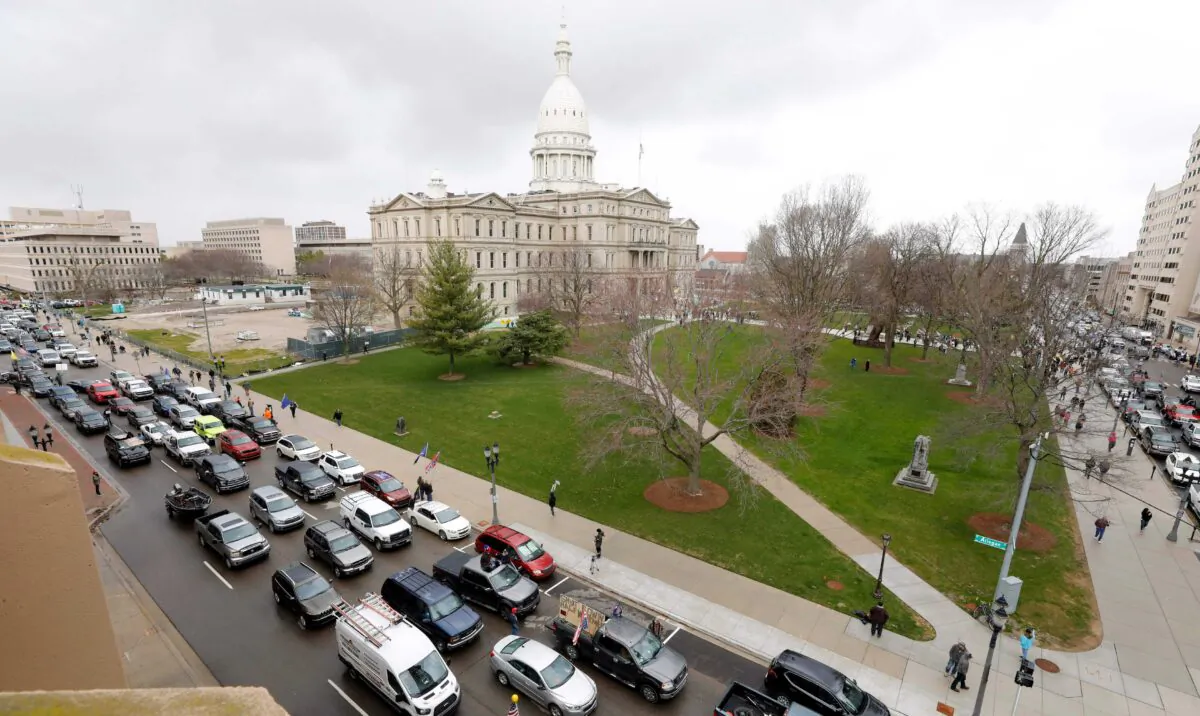 The Michigan state Capitol is seen in the background, as people in vehicles protest lockdown orders, in Lansing, Mich., on April 15, 2020. (Jeff Kowalsky/AFP via Getty Images)