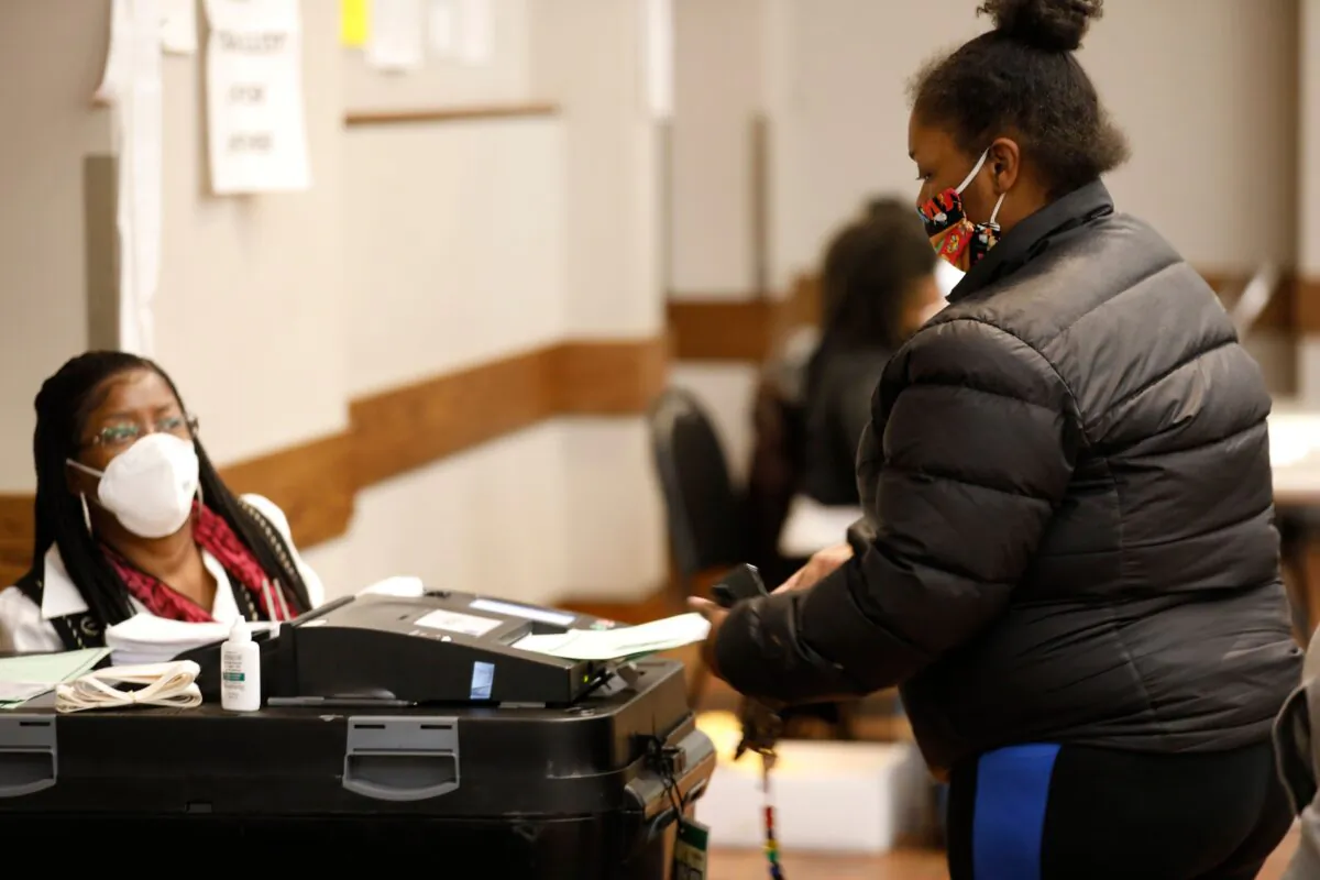 A voter puts her ballot in the tabulation machine after voting in the 2020 general election. (Jeff Kowalsky/AFP via Getty Images)