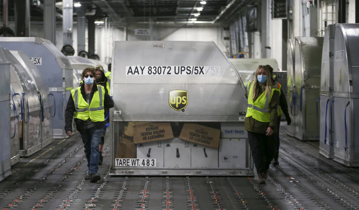 UPS employees move one of two shipping containers containing the first shipments of the Pfizer and BioNTech COVID-19 vaccine inside a sorting facility at UPS Worldport in Louisville, Ky., on Dec. 13, 2020. (Michael Clevenger/Pool/Getty Images)