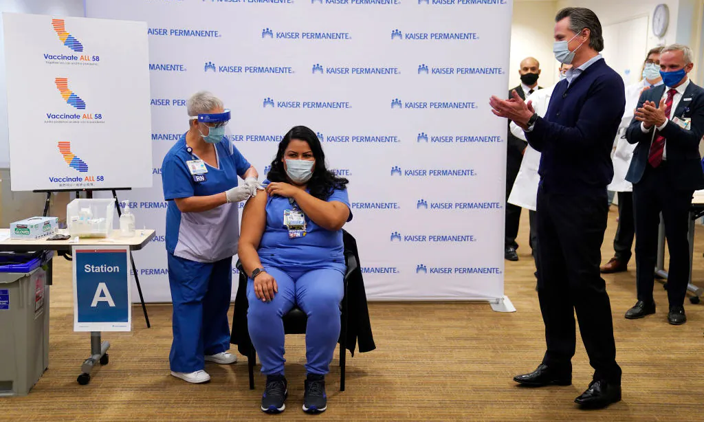 Gov. Gavin Newsom watches as ICU nurse Helen Cordova receives the Pfizer-BioNTech COVID-19 vaccine at Kaiser Permanente Los Angeles Medical Center in Los Angeles, Calif., on Dec. 14, 2020. (Jae C. Hong-Pool/Getty Images)
