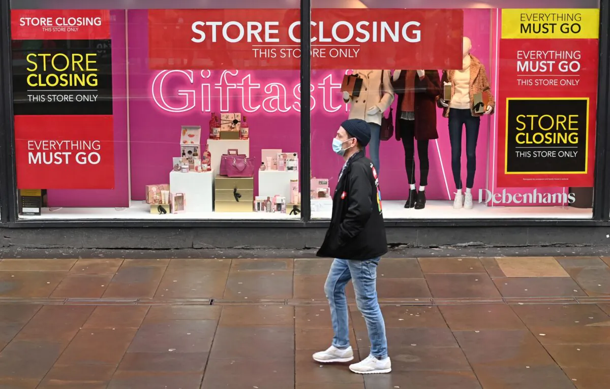 A pedestrian wears a mask as he walks past "Store Closing" signs in the window display of a Debenhams in Manchester, northern England, on Dec. 2, 2020. (Paul Ellis/AFP via Getty Images)