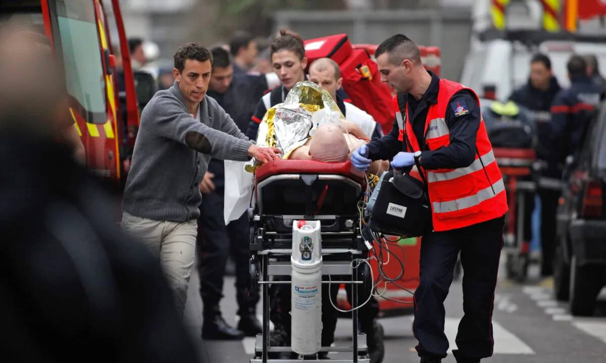 An injured person is transported to an ambulance after a shooting at the French satirical newspaper Charlie Hebdo's office in Paris, on Jan. 7, 2015. (Thibault Camus/AP Photo)