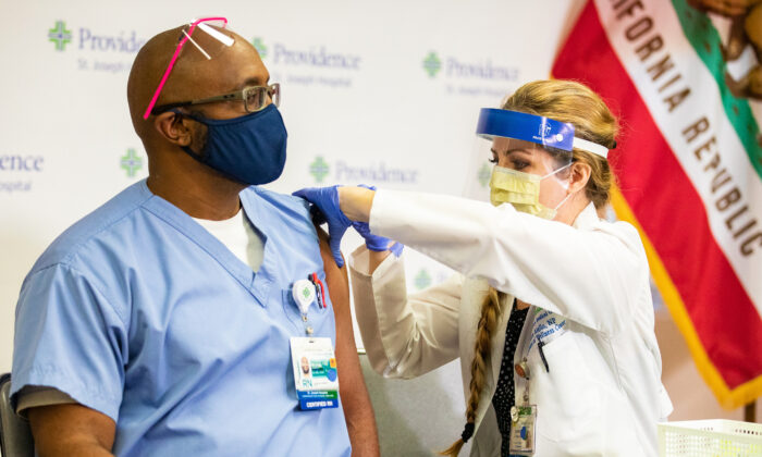 Registered nurse Michael Lowman (L) receives the first Pfizer COVID-19 vaccine injection in Orange County at St. Joseph Hospital in Orange, Calif., on Dec. 16, 2020. (John Fredricks/The Epoch Times) 