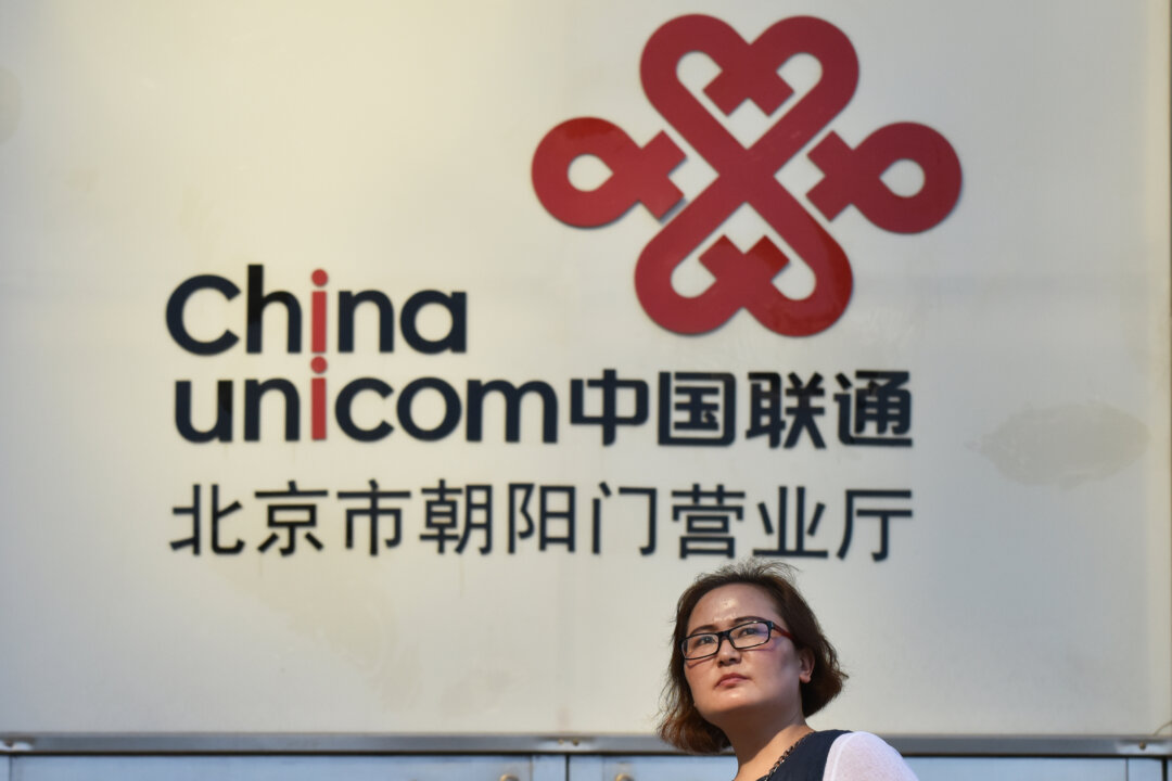 A woman walks past a China Unicom sign in Beijing on August 17, 2017.
(Greg Baker/AFP via Getty Images)