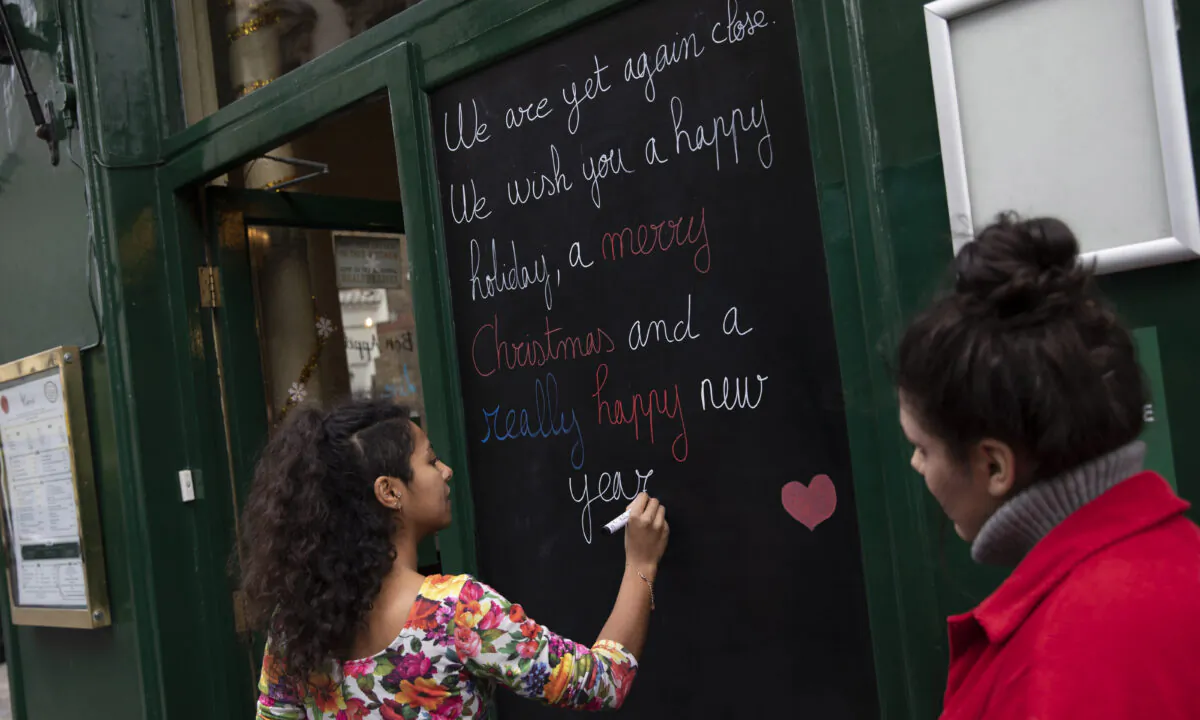 A restaurant worker at Le Garrick in Covent Garden writes a sign to customers in London on Dec. 16, 2020. (Dan Kitwood/Getty Images)