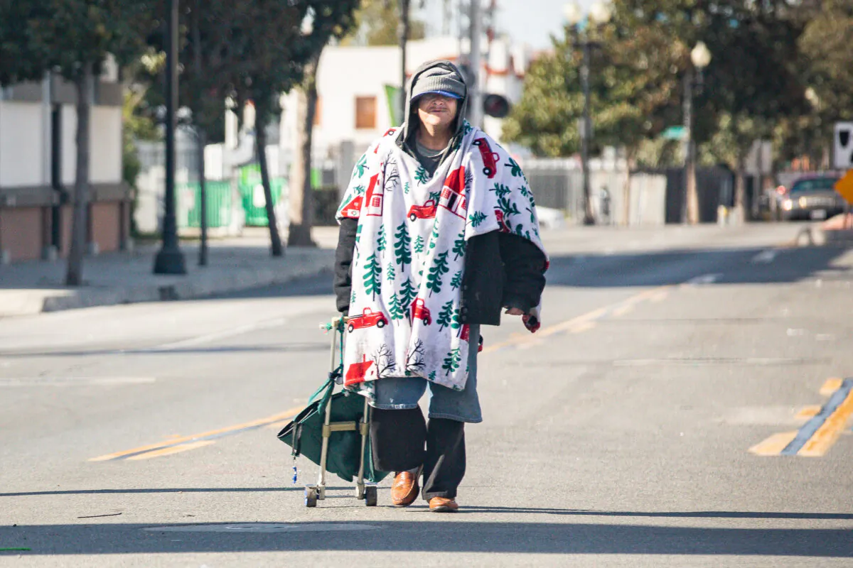 A homeless man walks in the middle of the road in Santa Ana, Calif., on Dec. 17, 2020. (John Fredricks/The Epoch Times)