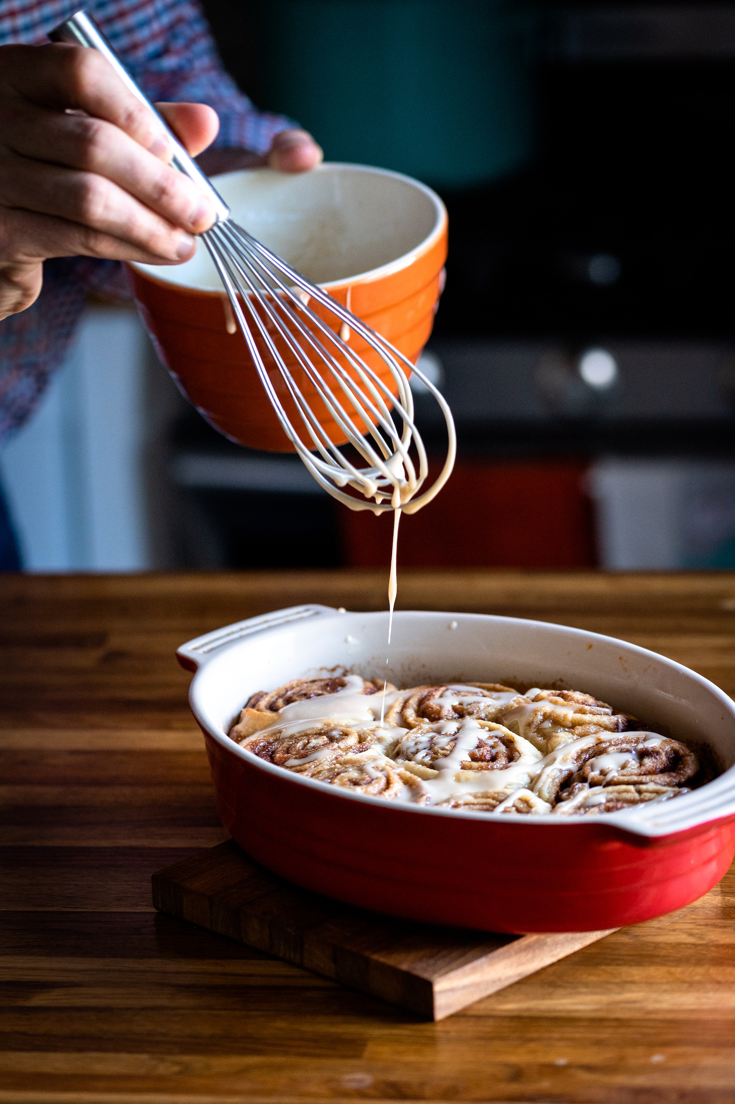 pouring icing over cinnamon rolls